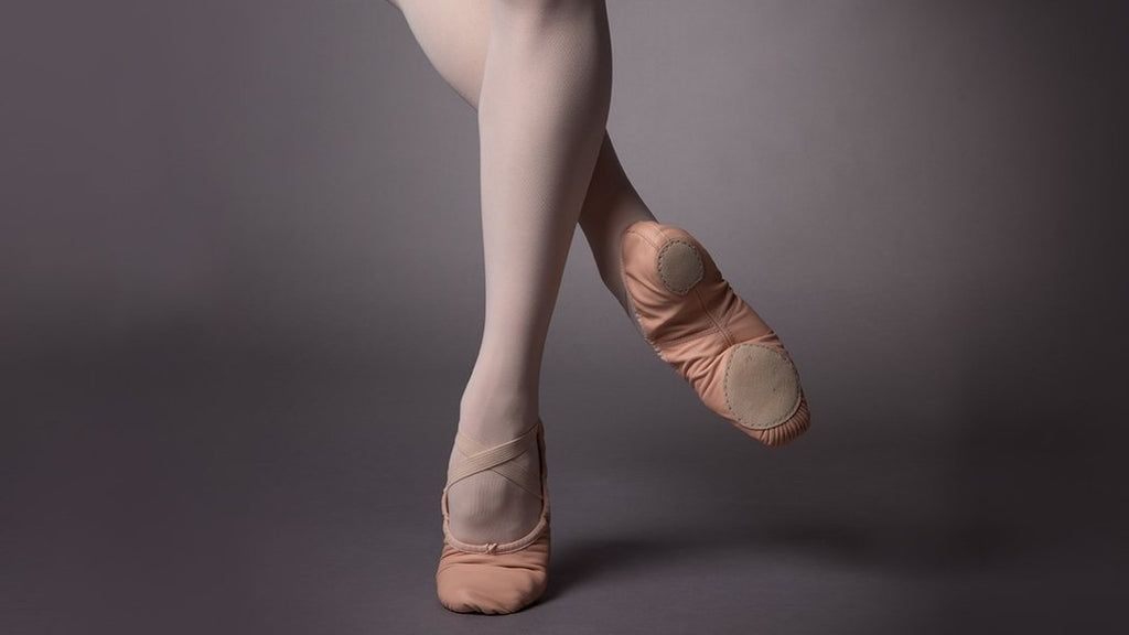 The legs of a female ballet dancer wearing Precision ballet flat shoes and showing off the suede outsole 