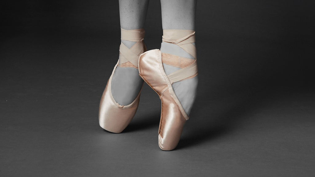 The feet of a ballet dancer dancing en pointe wearing the Balance Lisse pointe shoes