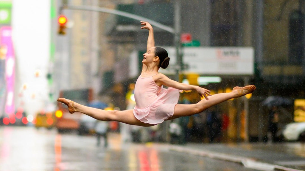 A young ballet dancer leaping through New York City wearing pink BLOCH leotard and ballet flat shoes 